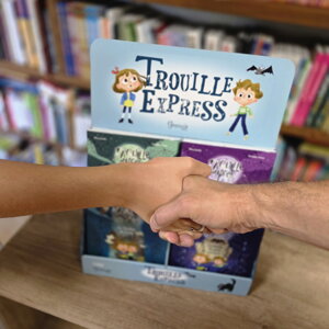 Détail d'une poignée de main devant un présentoir PLV en carton garni de livres